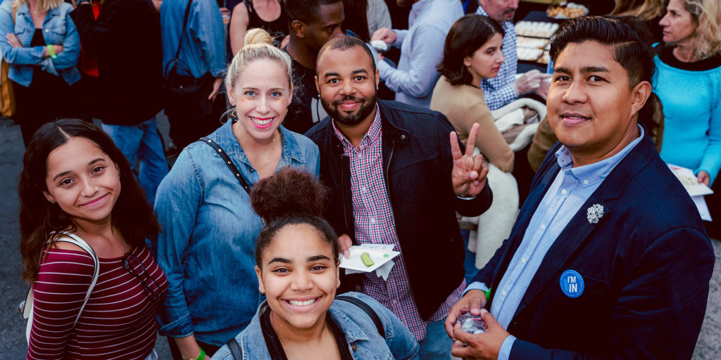 A group of people smile together at an Everyone In event